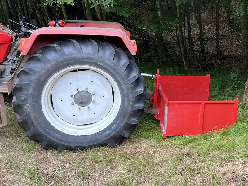 Traktor a lekaszált füvön az erdő szélén